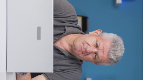 Vertical-video-of-Home-office-worker-man-looking-annoyed-at-camera.